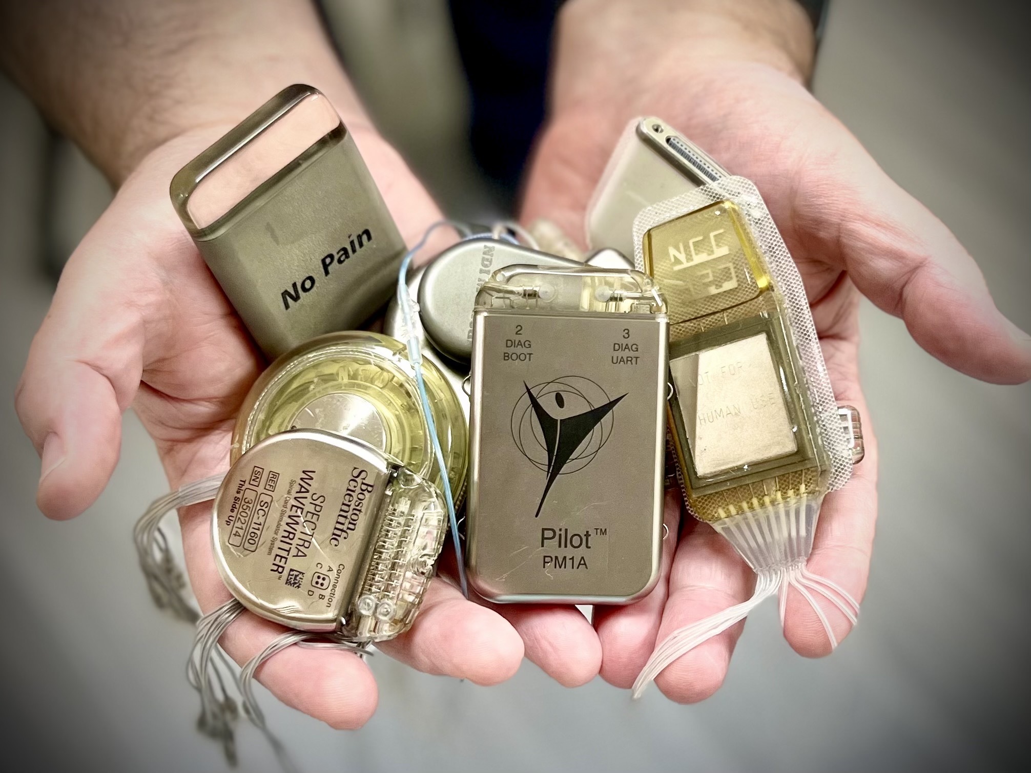 Hands holding a collection of abandoned implantable neural devices